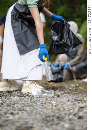 Volunteers wearing aprons and gloves in a cleanup activity. Holding trash bags filled with garbage. Protecting the environment by cleaning up litter 134722554