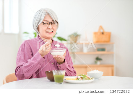 A senior woman with gray hair who eats yogurt and dairy products for breakfast (bifidobacteria, lactic acid bacteria, dairy products, gut health). A senior woman with gray hair who eats yogurt and dairy products for breakfast (bifidobacteria, lactic acid bacteria, dairy products, gut health). 134722922