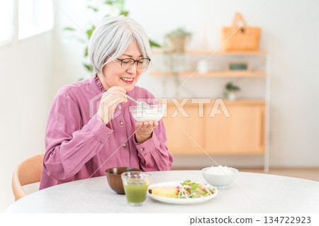 A senior woman with gray hair who eats yogurt and dairy products for breakfast (bifidobacteria, lactic acid bacteria, dairy products, gut health). A senior woman with gray hair who eats yogurt and dairy products for breakfast (bifidobacteria, lactic acid bacteria, dairy products, gut health). 134722923