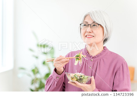 A gray-haired senior woman eating salad for health A gray-haired senior woman eating salad for health 134723396