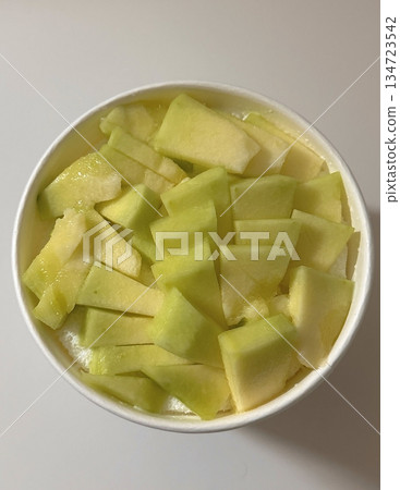 Swirled yogurt ice cream dessert served in a cup, smooth creamy texture with glossy surface, topped with fresh fruit pieces, highlighting its refreshing and inviting appearance in detail 134723542