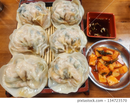 Steamed or fried mandu dumplings served alongside fermented kimchi, creating a classic Korean pairing that combines savory, tender dumplings with spicy, tangy, and flavorful fermented vegetables Steamed or fried mandu dumplings served alongside fermented kimchi, creating a classic Korean pairing that combines savory, tender dumplings with spicy, tangy, and flavorful fermented vegetables 134723570