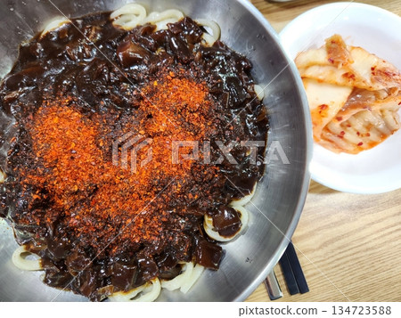 A bowl of jajangmyeon featuring chewy noodles coated in rich black bean sauce, topped with diced pork and vegetables. This iconic Korean-Chinese dish offers a savory and hearty flavor. 134723588