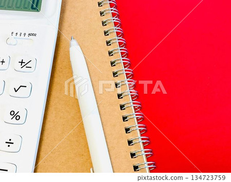 White calculator, brown notebook and white pen (red background) White calculator, brown notebook and white pen (red background) 134723759