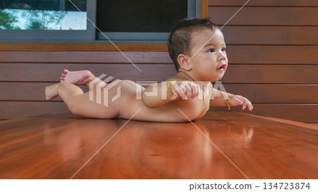 asian baby girl sitting in wooden table 134723874