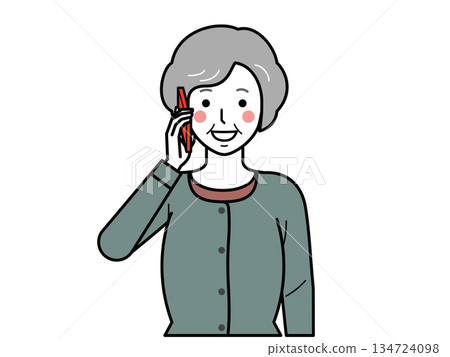 Front view. An elderly woman wearing a cardigan talking on a smartphone. 134724098