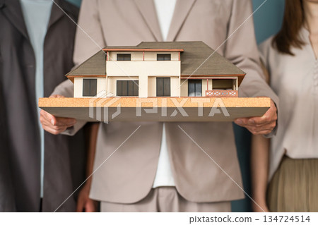Male staff of a house manufacturer, design office, or construction company holding an architectural model or house model Male staff of a house manufacturer, design office, or construction company holding an architectural model or house model 134724514