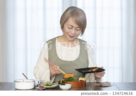Senior woman making lunch in the kitchen Senior woman making lunch in the kitchen 134724616