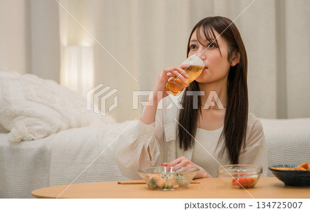 Young Asian woman having a drink in the bedroom at home (beer, home drinking, drinking habits) Young Asian woman having a drink in the bedroom at home (beer, home drinking, drinking habits) 134725007