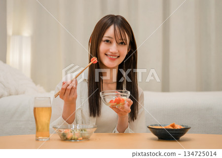 一位年輕的亞洲女性在家裡的臥室裡一邊吃零食一邊喝酒(啤酒,在家喝酒,飲酒習慣) 一位年輕的亞洲女性在家裡的臥室裡一邊吃零食一邊喝酒(啤酒,在家喝酒,飲酒習慣) 134725014