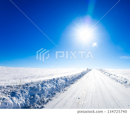 Winter scenery of Biei, Hokkaido, with blue sky, sun and packed snow and icy roads 134725740