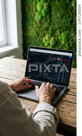 Person Working on Laptop in Eco Friendly Office with Green Moss Wall 134726084