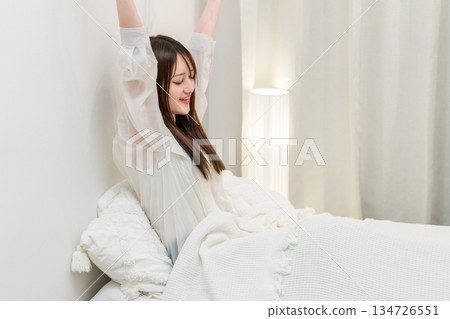 A woman stretching in her bedroom in the morning after a good night's sleep 134726551