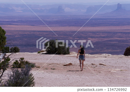Distant view of Monument Valley from Muhle Point and a woman's back Distant view of Monument Valley from Muhle Point and a woman's back 134726992