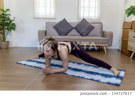 Asian woman in her 50s warms up on a yoga mat on the floor before starting Asian woman in her 50s warms up on a yoga mat on the floor before starting 134727617
