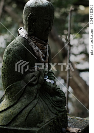 Coins offered to a moss-covered stone Buddha Coins offered to a moss-covered stone Buddha 134728362