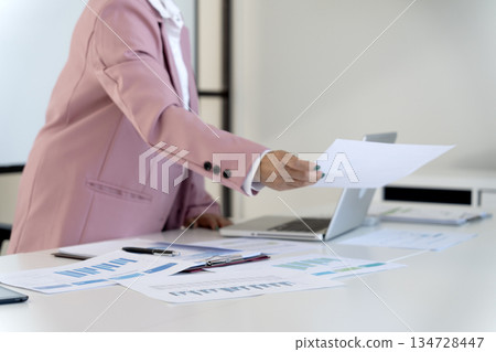 Senior female executive is standing looking at documents and computers 134728447