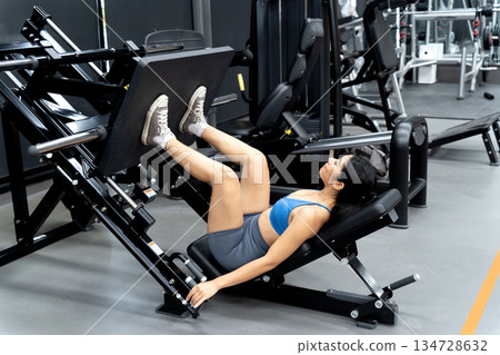 Young woman is exercising, focusing on building leg muscles Young woman is exercising, focusing on building leg muscles 134728632