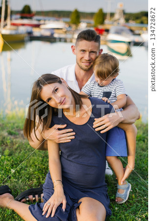 Happy Family Sitting Together Near Boats and Marina Happy Family Sitting Together Near Boats and Marina 134728672