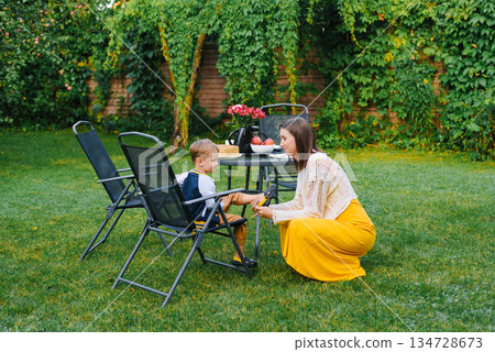 Mother Helping Son With Shoes In Garden Mother Helping Son With Shoes In Garden 134728673