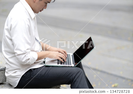 Business man in casual clothes is sitting and using laptop on lap 134728728