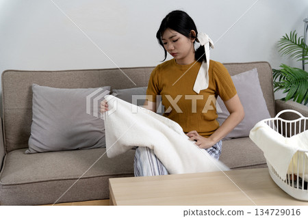 A young woman is sitting in the living room folding clothes  modern woman 134729016