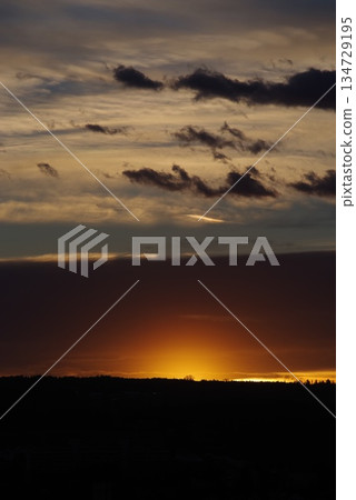 The sky is dark and cloudy with a bright orange sun in the background The sky is dark and cloudy with a bright orange sun in the background 134729195