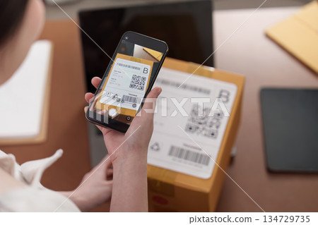 Scanning QR code on package for delivery tracking 134729735