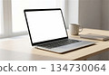 Mockup image of laptop with blank white screen on wooden desktop with coffee cup and other items 134730064
