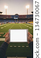 Tablet with a blank screen inside a football stadium. Concept of sports technology, live analytics, coaching, and professional digital tools. Perfect for advertising and stock. 134730067