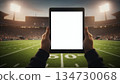Tablet with a blank screen inside a football stadium. Concept of sports technology, live analytics, coaching, and professional digital tools. Perfect for advertising and stock. 134730068