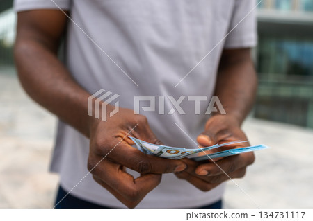 Man hands holding money dollar bills on urban street outdoor. Businessman hands counting currency money outdoors near office bank building. Unrecognizable man holding cash. Finance economy banking Man hands holding money dollar bills on urban street outdoor. Businessman hands counting currency money outdoors near office bank building. Unrecognizable man holding cash. Finance economy banking 134731117
