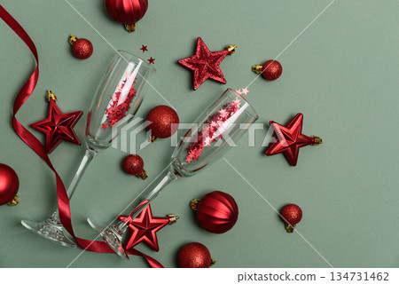 Champagne Flutes and Red Christmas Decorations on Green Background . Happy New Year or Christmas celebration Champagne Flutes and Red Christmas Decorations on Green Background . Happy New Year or Christmas celebration 134731462