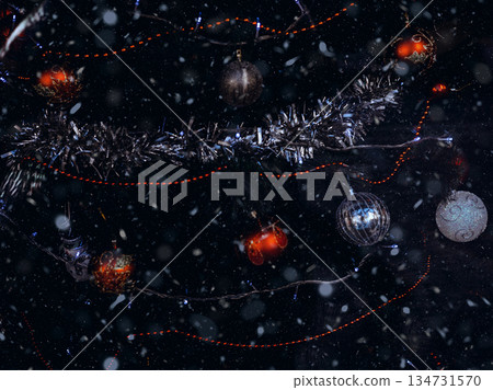 Festive winter backdrop. Close-up of a Christmas tree with red and silver ornaments, garlands and falling snow. Wintertime magic. New Year 2026 134731570