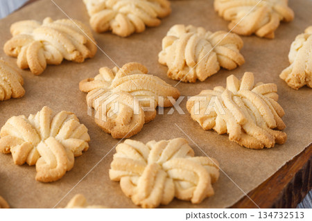 Homemade butter spritz cookies baking on parchment paper Homemade butter spritz cookies baking on parchment paper 134732513