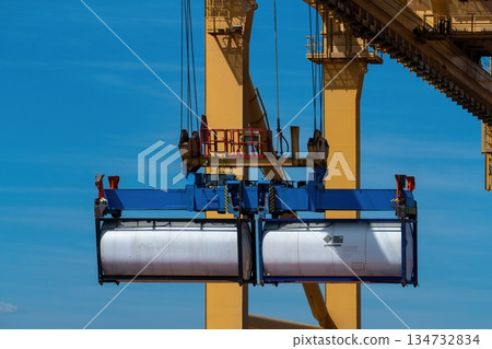 Port crane lifting two ISO tank containers against blue sky 134732834