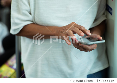 Selective focus on the hand of old man while using the mobile phone Selective focus on the hand of old man while using the mobile phone 134733456