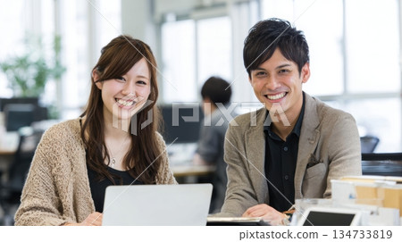 年輕的日本男女同事對著筆記型電腦微笑 134733819