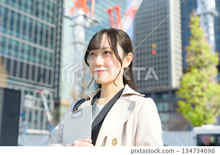 一名身穿西裝的女子在建築工地拿著一個活頁夾。 134734698