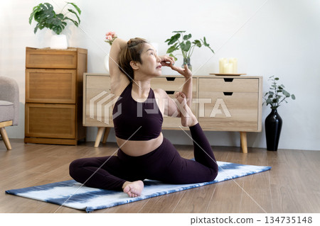 Asian 50+ year old woman is doing a seated yoga mat stretching exercise to demonstrate Asian 50+ year old woman is doing a seated yoga mat stretching exercise to demonstrate 134735148