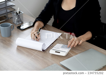senior business woman is using a calculator senior business woman is using a calculator 134735202