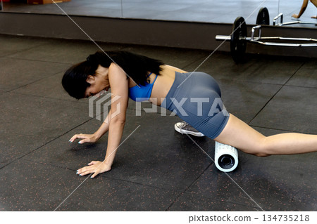 young woman is exercising while lying down using a circular device to roll on the floor 134735218