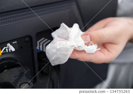 Person's hand diligently cleaning accumulated dust from an electronic device's rear port area with a dirty wet wipe, highlighting essential maintenance 134735263