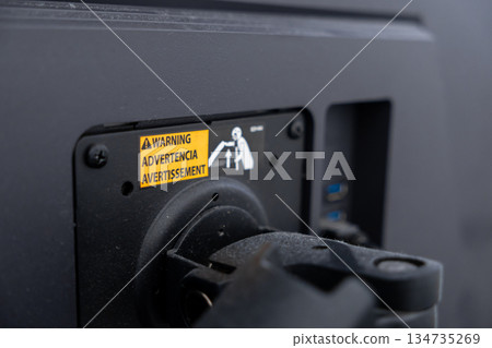 Electronic display back with yellow warning label WARNING ADVERTENCIA AVERTISSEMENT and safety graphic, guiding users on proper lifting and careful equipment handling Electronic display back with yellow warning label WARNING ADVERTENCIA AVERTISSEMENT and safety graphic, guiding users on proper lifting and careful equipment handling 134735269