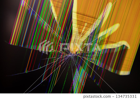 Severely cracked electronic screen with vibrant pixel lines radiating from a central impact, symbolizing technology failure, digital glitch, data corruption, and repair 134735331
