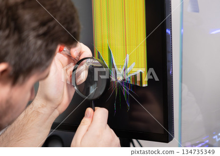 Expert technician carefully examining a severely damaged computer monitor display with a visible cracked screen and vibrant pixel lines for electronic repair Expert technician carefully examining a severely damaged computer monitor display with a visible cracked screen and vibrant pixel lines for electronic repair 134735349