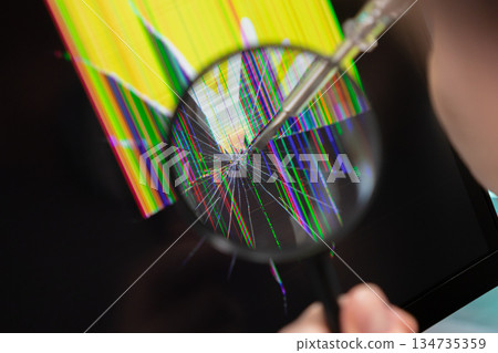Magnifying glass examining a severely cracked electronic screen displaying colorful dead pixels and a screwdriver, indicating crucial technology repair service 134735359