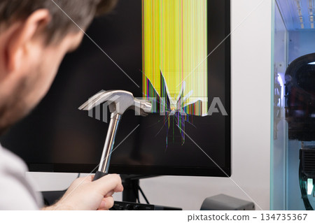 Man holds hammer near computer monitor with shattered screen, showing colorful lines, representing technology breakdown, digital frustration, and system failure Man holds hammer near computer monitor with shattered screen, showing colorful lines, representing technology breakdown, digital frustration, and system failure 134735367