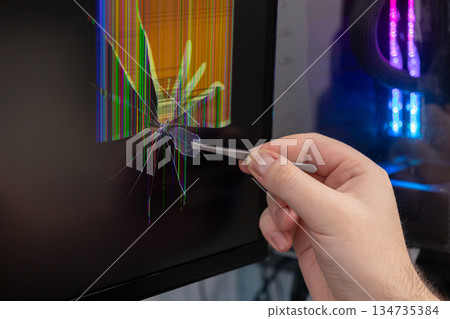A person's hand uses tweezers to meticulously remove a tiny glass shard from a severely cracked computer monitor, demonstrating electronic device screen repair A person's hand uses tweezers to meticulously remove a tiny glass shard from a severely cracked computer monitor, demonstrating electronic device screen repair 134735384