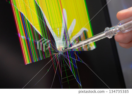 Hand pointing a clear screwdriver at a severely cracked electronic screen with vibrant pixel lines, illustrating digital device damage and repair necessity Hand pointing a clear screwdriver at a severely cracked electronic screen with vibrant pixel lines, illustrating digital device damage and repair necessity 134735385